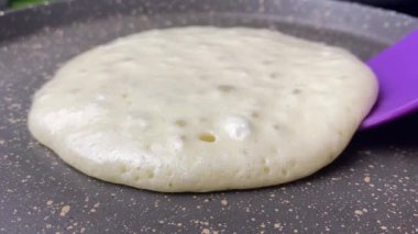 Top shot pancake cooking process in a frying pan. Close up shot of spatula flipping pancake in hot frying pan. Making pancake homemade recipe pancake for family delicious breakfast meal.4k footage.