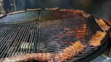 Lezzetli kaburgalar ateşin arka planındaki ızgarada kızarıyor..