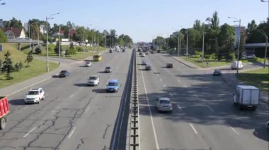 Şehirdeki trafik trafiğinin 4K UHD zaman çizelgesi. Köprüden hızla geçen arabalara tepeden bakıyor. Şehir yaşamı ve taşımacılığı