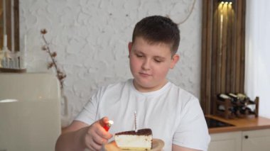 Beyaz bir çocuğun doğum günü pastasında mum üfleyip dilek tuttuğu yakın plan. Mutlu güzel bir çocuğun evde doğum gününü kutlayan portresi..