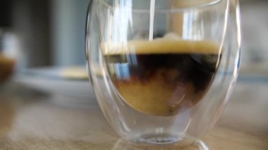 Adding coffee creamer into black coffee. Slow motion cream pouring in a cup of black coffee