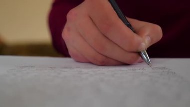 Kağıt üzerinde kalemle yazan bir adamın yakın çekimi.