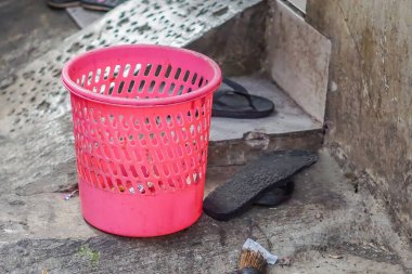 Pink plastic trash basket in front of the house
