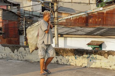 Jakarta, Endonezya - 5 Mart 2023: Asfalt yolda yürüyen bir hurda koleksiyoncusunun portresi