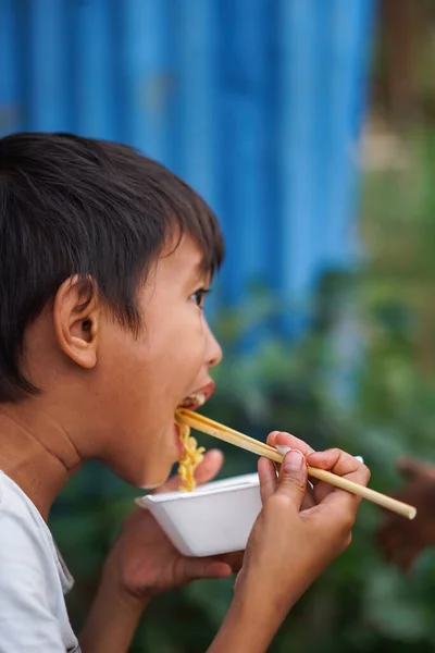 Stock image Jakarta, Indonesia - December 11, 2022: Portrait of a hungry asian boy eating noodles using chopsticks.