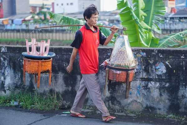 Jakarta, Endonezya - 3 Nisan 2023: Kızarmış tofu satan Asyalı bir adam mallarını satarken yaya olarak dolaşıyor.