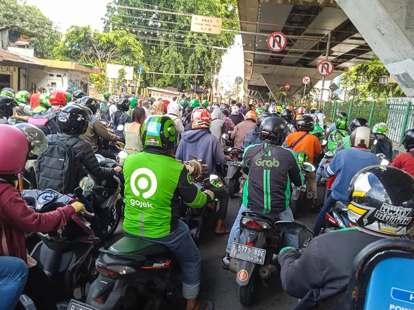 Jakarta, Endonezya - 22 Şubat 2023: Geçen bir tren trafik sıkışıklığına yol açarken bir sıra motosiklet durdu.