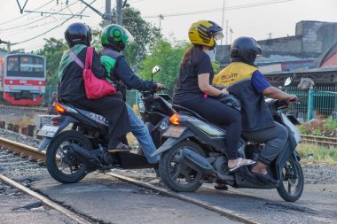 Jakarta, Endonezya - 28 Mayıs 2023: Sabah bir demiryolu geçidinde motosikletçiler