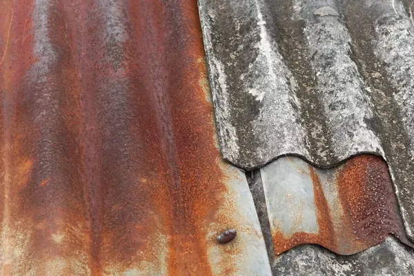 Eski kıvrımlı asbestlerle dolu paslanmış teneke bir çatı. Sunumlar için illüstrasyon olarak kullanılabilir.
