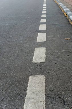 Asfalt yolda noktalı beyaz bir çizgi. Bu çizgi, noktalı çizginin kenarındaki sürücülerin diğer tarafa geçmesini sağlar..