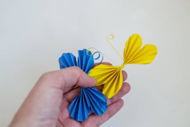 female hand holding colorful flowers in a glass on a blue background
