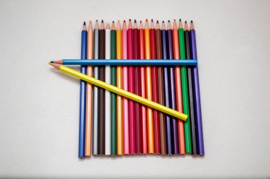 Üst üste beyaz bir arka plan üzerinde renkli kalemler