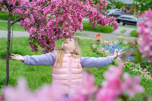 春の庭に桜が咲くピンクのドレスの女の子 — ストック写真