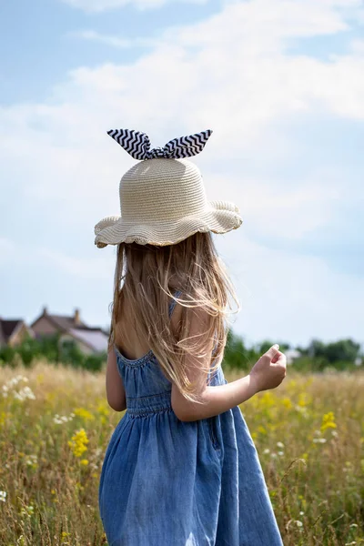 戴着白帽的小女孩在田野里散步 — 图库照片