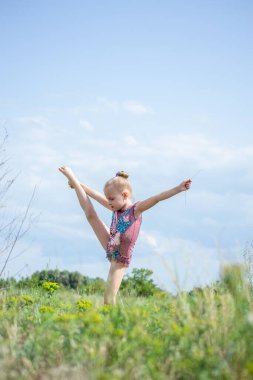 Güzel bir mayo giymiş bir jimnastikçi doğada elementler sergiliyor.