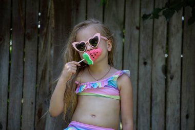 Yazın yüzünde maske olan mayolu küçük bir kız.