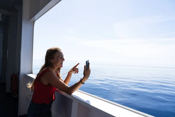 Genç sarışın turist feribotta akıllı telefonuyla selfie çekiyor.. 