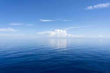 Sabah gökyüzünün önü açık beyaz bulutlarla parlak mavi. Ve okyanus gün ışığının derinliklerinde. Sakinim, sakinim, rahatım. Doğal minimalist arkaplan ve doku, panoramik görünüm 