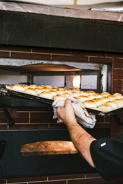 Tanınmayacak halde fırından lezzetli ekmeklerle tepsiyi çıkarıyor. Geleneksel Sicilya mutfağı. 