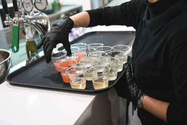 Siyah eldivenli tanınmayan garson tepside alkollü içecekler hazırlıyor.. 