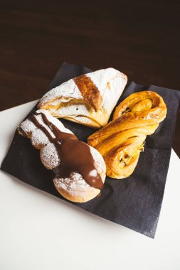 Bir sürü taze kruvasan, çikolata, fıstık, ahşap masa içi krema, yakın plan. Fransız pastası..