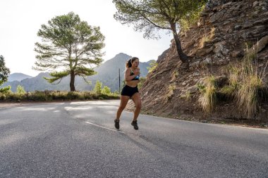 Dağ yolunda koşan formda bir bayan sporcu. Açık havada sıkı çalışan bir kadın.. 