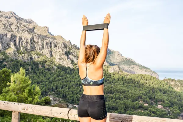 Genç sportif kadın lastik bantla dışarıda egzersiz yapıyor..