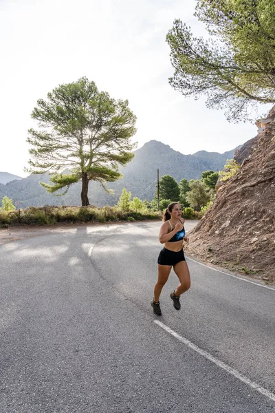 Fit female athlete running on mountain road.Sporty woman training hard outdoors.