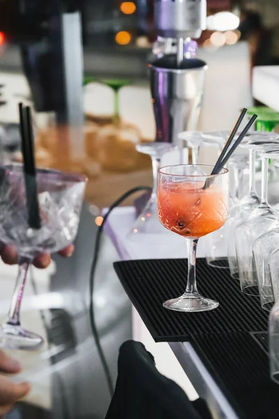 Siyah giyinmiş tanınmayan bir barmen portakal kokteyli ve meyve garnitürü servis ediyor.