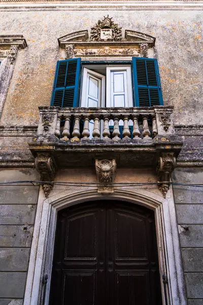 Süslü balkonu ve ahşap kapısı olan tarihi bir İtalyan cephesinin mimari ayrıntıları.