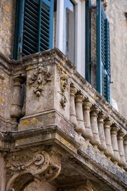 Tarihi bir Avrupa kasabasında heykel ve sütunlarla dolu eski bir taş balkonun ayrıntılı görüntüsü