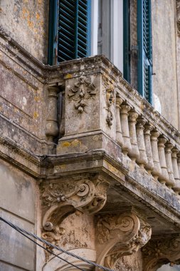 Tarihi bir Avrupa kasabasında heykel ve sütunlarla dolu eski bir taş balkonun ayrıntılı görüntüsü