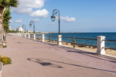 Güneşli sahil yolu palmiye ağaçları ve güney Avrupa şehrinde kumlu bir plajla kaplı.