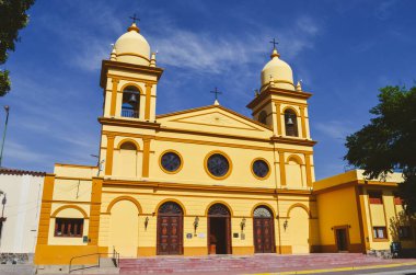 Arjantin 'de güneşli bir günde çan kuleleri ve yuvarlak pencereleri olan tarihi sarı kilise