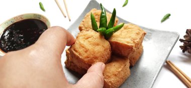 Kızarmış süt tofusu ya da Tahu susu goreng siyah soslu çubuklar ve beyaz arka planda yeşil kırmızı biber ile servis edilir. Endonezya 'dan geleneksel atıştırmalıklar