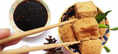 Kızarmış süt tofusu ya da Tahu susu goreng siyah soslu çubuklar ve beyaz arka planda yeşil kırmızı biber ile servis edilir. Endonezya 'dan geleneksel atıştırmalıklar