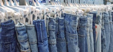 Variety of blue denim jeans thrift  on a hanging rack in store for sale at pasar senen. Jakarta, Indonesia clipart