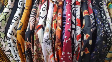 Üst üste soyut desenli bluz giyen kadın mağazada indirim yapıyor.