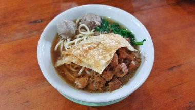 Ahşap masada lezzetli bir kase Mie Ayam. Endonezya Tavuğu Erişte Çorbası
