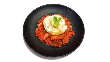 Siyah tabakta kırmızı pilav ve yumurta ve scallion servis edilir.