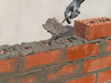 İnşaat işçisi inşaat alanına tuğla duvar kuruyor..