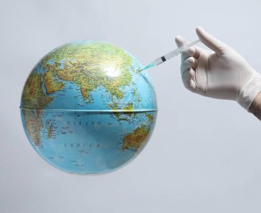 Tıbbi maskeli doktor elinde bir şırınga tutuyor..