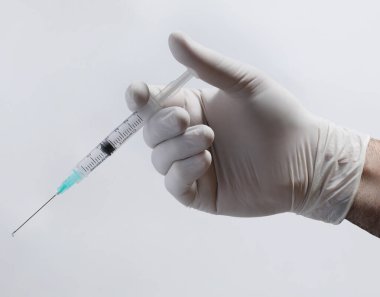 Elinde şırınga ve elinde iğne olan beyaz arka planda bir doktor.
