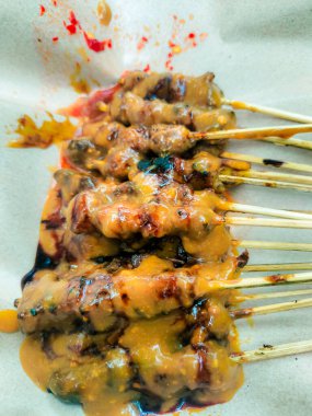 Endonezya usulü ızgara et satay şiş zengin, lezzetli fıstık sosuyla kaplanmış, sokak yemeklerinin özgünlüğü için bir parça parşömen kağıdına konulmuş..