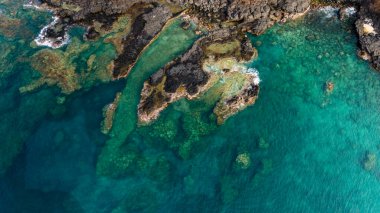 Temiz turkuaz suları olan kayalık bir kıyı şeridinin havadan görüntüsü..