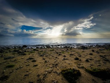 Sakin deniz manzarası, güneş ışınları bulutları delip geçiyor alacakaranlıkta sakin okyanus sularını..
