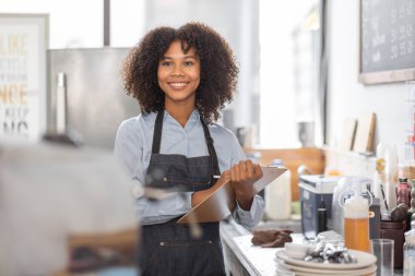 Afrikalı kadın kahve dükkanı küçük işletme sahibi tezgahın önünde durup stok kontrolü yapıyor. afro saç çalışanı Barista girişimci.