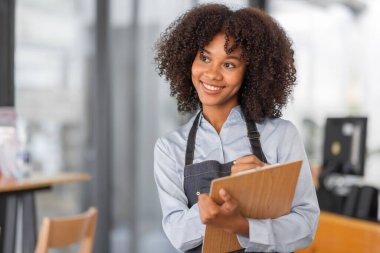 Afrikalı kadın kahve dükkanı küçük işletme sahibi tezgahın önünde durup stok kontrolü yapıyor. afro saç çalışanı Barista girişimci.