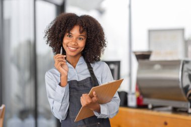 Afrikalı kadın kahve dükkanı küçük işletme sahibi tezgahın önünde durup stok kontrolü yapıyor. afro saç çalışanı Barista girişimci.