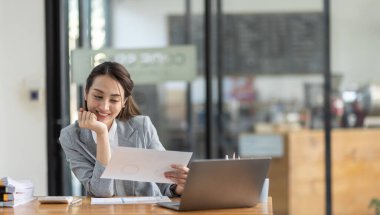 Bir ofis masası, vergi, rapor, muhasebe, istatistik ve analitik araştırma konseptinde matematik finansmanı yapmak için hesap makinesi ve laptop kullanan mutlu Asyalı iş kadını